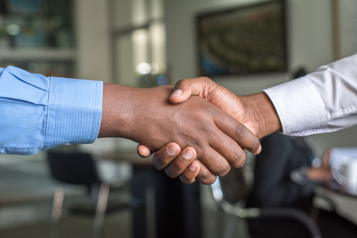 Two people shaking hands over a signed agreement